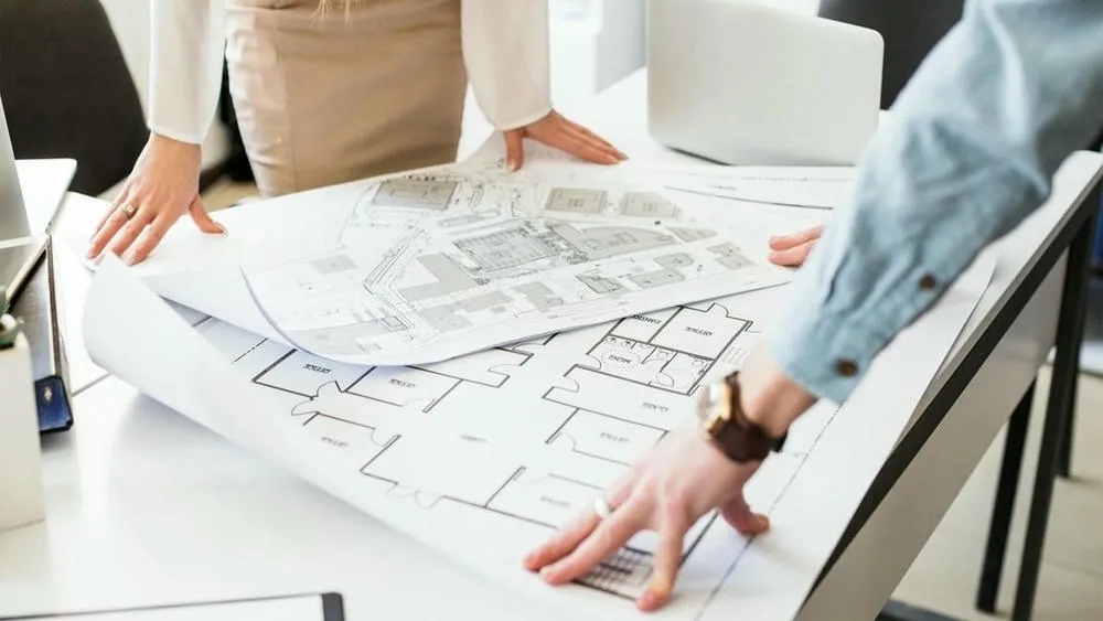 Ingenieros y arquitectos analizando planos para compatibilización de proyectos de construcción.