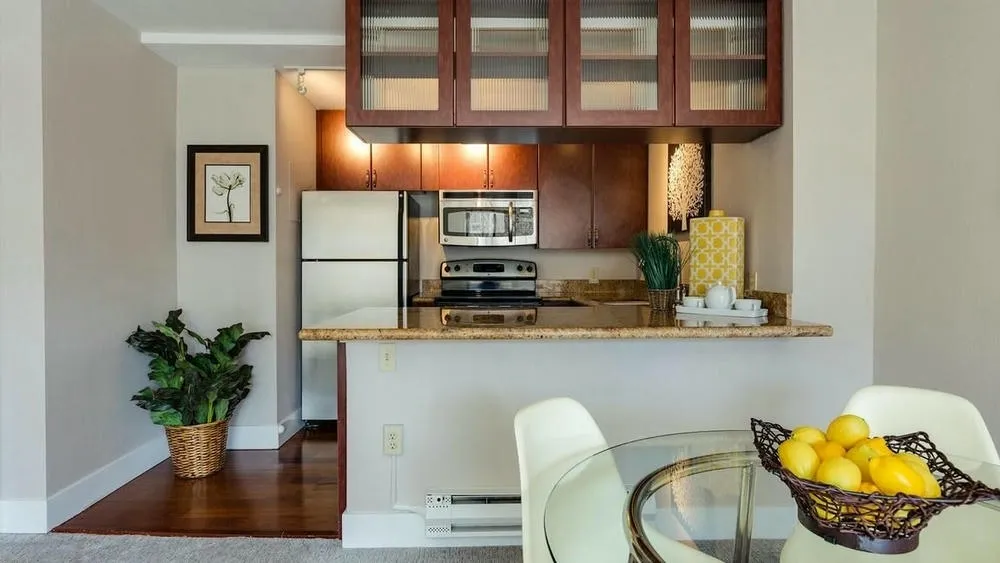 Compact kitchen integrated into the dining area, with counter and cabinets, ideal for optimizing space in apartments.