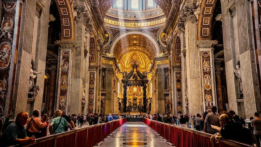 Interior da Basílica de São Pedro, com corredores amplos, colunas e teto ricamente decorados em estilo barroco.