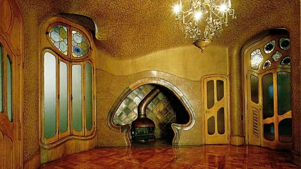 Interior da Casa Batlló com lareira de formas orgânicas e janelas com vitrais, no estilo Art Nouveau.