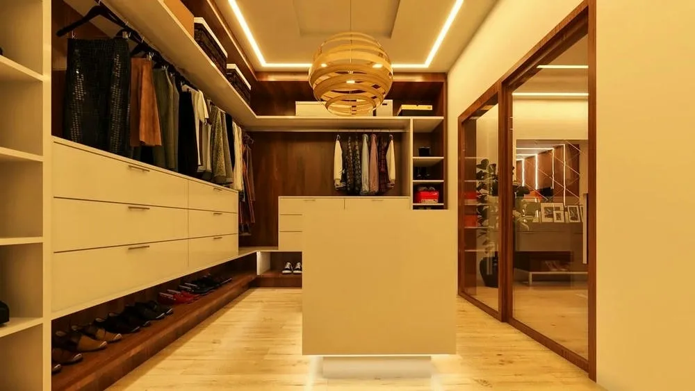 Large and luxurious closet with central island, wooden cabinets and recessed ceiling lighting.