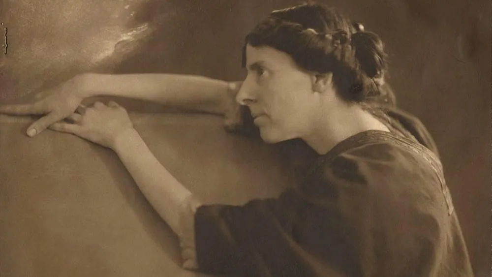 Portrait of Marion Mahony Griffin, with her hands resting on a surface, in black and white.