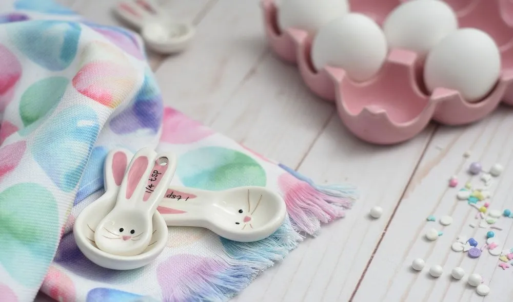 Mesa de Pascua con vajilla clara y servilletas decoradas.