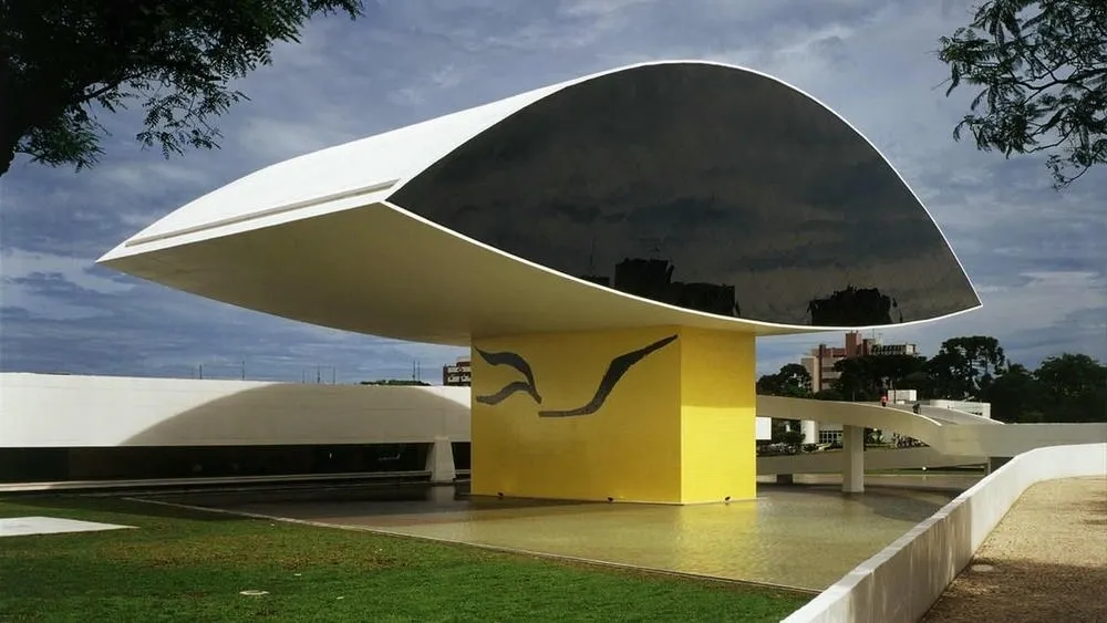 O Museu Oscar Niemeyer em Curitiba, Paraná, conhecido como 'Museu do Olho', com sua estrutura distintiva refletida em um espelho d'água.