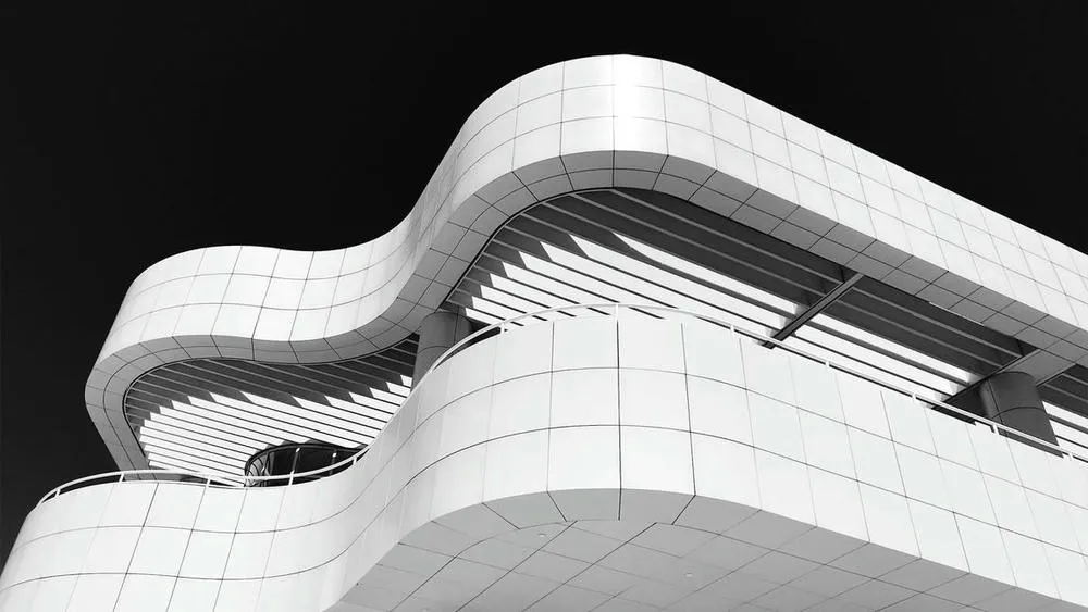 Modern building facade with curves and volumes in white and gray tones, highlighting the clean aesthetic and absence of ornaments.