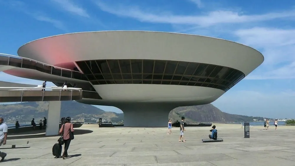 Niterói Contemporary Art Museum with its circular shape and spiral ramp, contrasting with the blue sky and landscape in the background, an example of minimalism in Brazilian architecture.