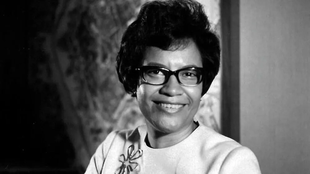 Black and white portrait of Norma Merrick Sklarek, smiling and wearing glasses.