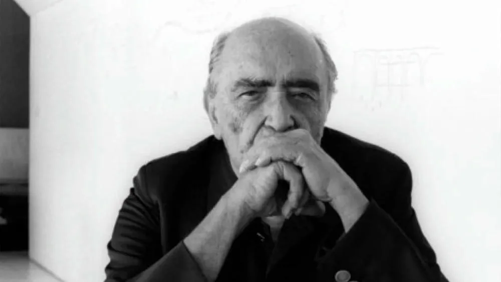 Retrato em preto e branco de Oscar Niemeyer, arquiteto famoso, em pose pensativa.