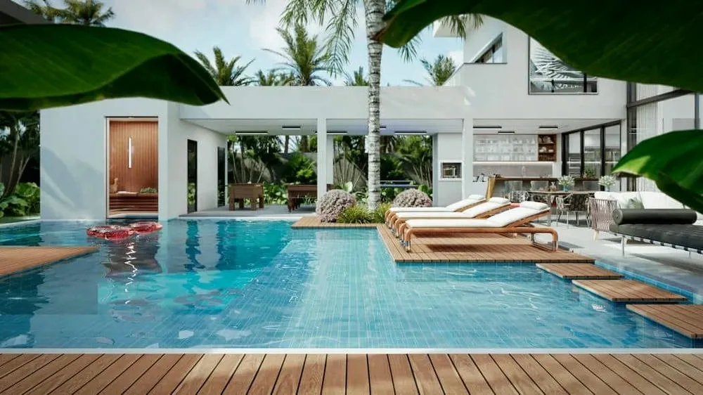 Pool with loungers on a wooden deck and gourmet area in the background in a luxury house.