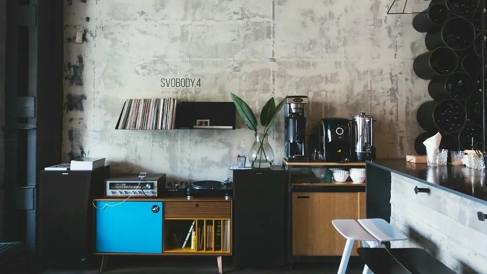 Ambiente com paleta de cores neutras, incluindo cinza e branco, combinadas com detalhes em madeira escura e metal, caracterizando o estilo industrial.