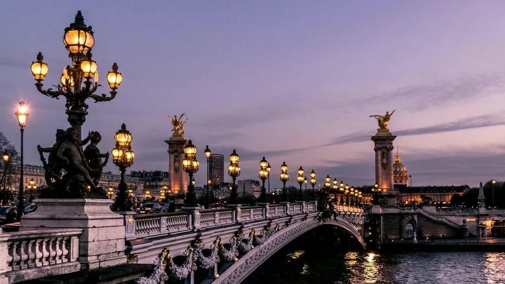 Pont Alexandre III in Paris, France, with its ornate lampposts and golden statues, at dusk.