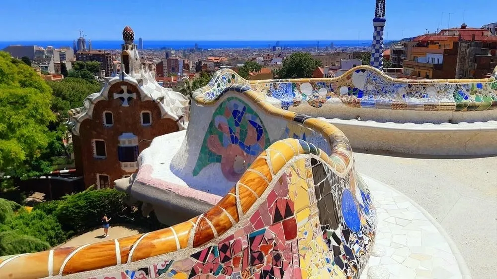 Bench decorated with colorful mosaics in Park Güell in Barcelona, Spain, with a view of the city.