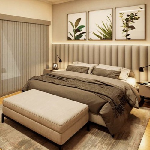 Quarto de casal com cama king-size, cabeceira estofada, quadros botânicos, iluminação em LED e banqueta na frente da cama.