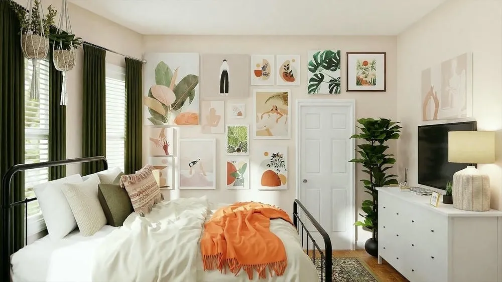 Um quarto com uma cama de ferro preta e roupas de cama brancas e laranja. A parede ao fundo está decorada com uma galeria de quadros abstratos e com temas botânicos. Há plantas em vasos pendurados, em uma prateleira e uma grande planta em um vaso preto ao lado de uma cômoda branca com uma TV. O ambiente é iluminado e acolhedor.