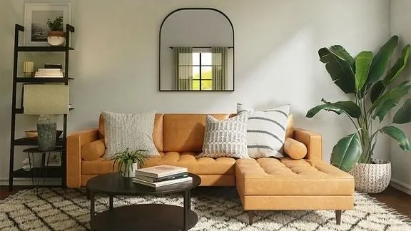 Sala de estar com sofá marrom, espelho decorativo preto e plantas, demonstrando a aplicação da regra 60-30-10 com cores claras e pontos de destaque.