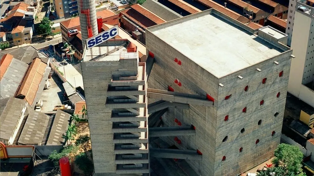 Vista aérea del SESC Pompeia, mostrando sus volúmenes de concreto aparente y la torre con el letrero 'SESC'.