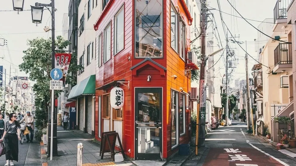 Street in Tokyo, Japan, with buildings of traditional and modern architecture, and people walking.