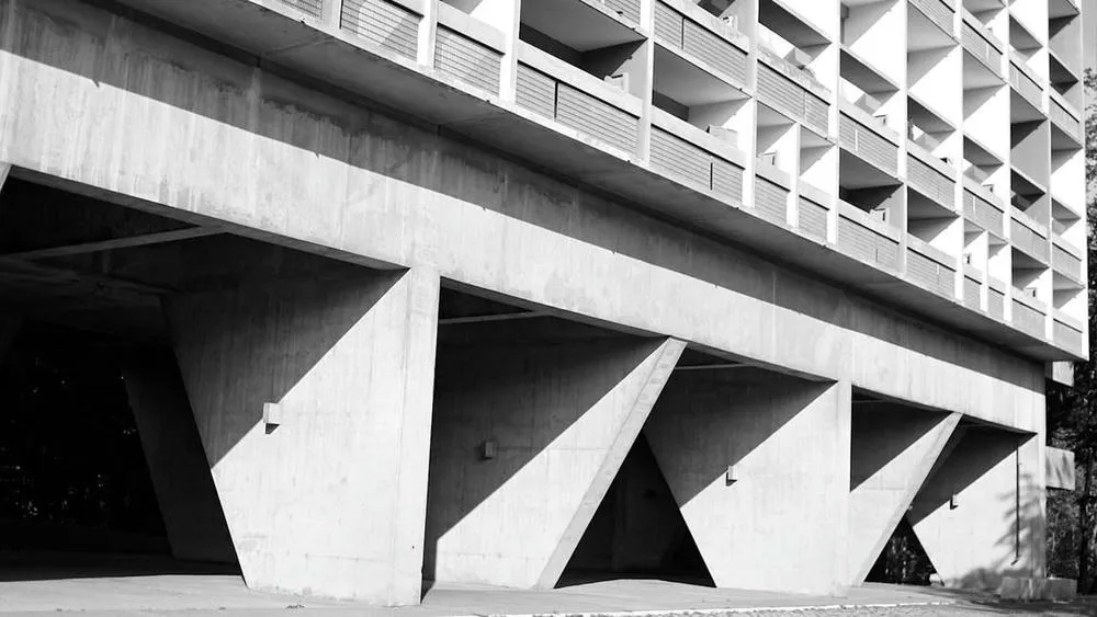 Bottom view of Le Corbusier's Unité d'Habitation, highlighting the pilotis and imposing black and white structure, a modernist icon.
