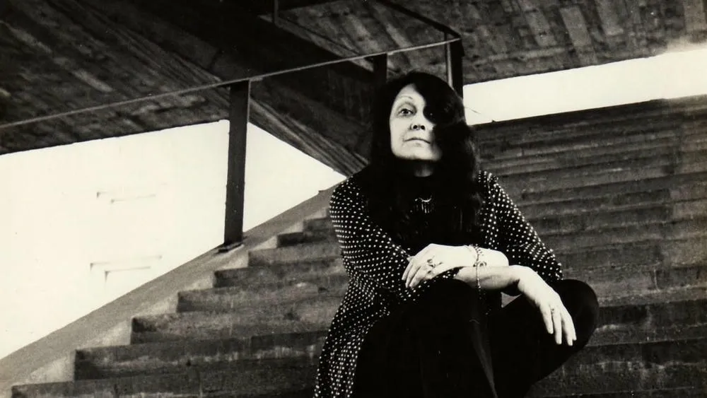 Lina Bo Bardi in an old photo, with a thoughtful expression, reflecting her passion for architecture and social context.